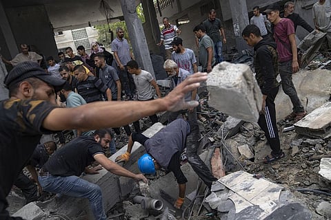 Palestinians look for survivors in a building destroyed during Israeli bombardment in Rafah refugee camp in Gaza Strip. (Photo | AP)
