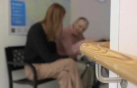 Nursing home manager Caroline Wahlberg (L) chats with an elderly man at the fake bus stop. (Photo | AFP)