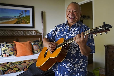 Charles Nahale plays the only guitar he took with him from the wildfire on Tuesday, Oct. 10, 2023, in Lahaina, Hawaii. (Photo | AP)
