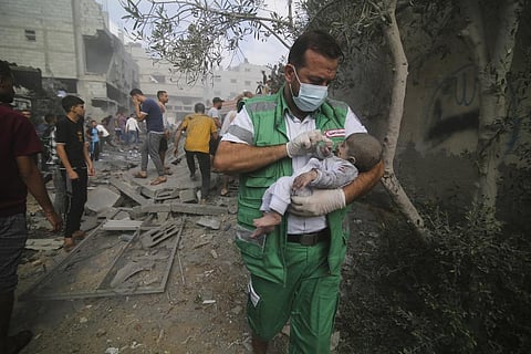 Palestinian medic takes a baby pulled out of buildings destroyed in the Israeli bombardment of the Gaza Strip in Rafah. (Photo | AP)