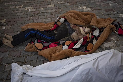 The bodies of a father and his child killed in the Israeli bombardment of the Gaza Strip, lie in front of the morgueat Al Aqsa Hospital, Oct 22, 2023. (Photo | AP)