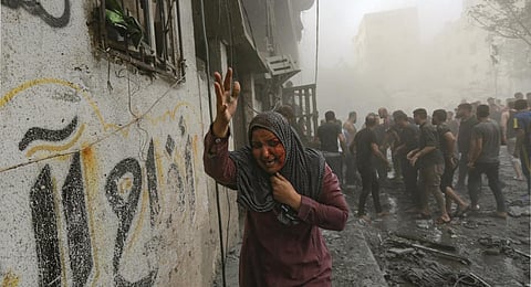 A wounded Palestinian woman runs following Israeli airstrikes that targeted her neighbourhood in Gaza City. (Photo | AP)