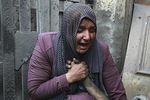 A wounded Palestinian woman cries as she holds the hand of her dead relative in Gaza City, Oct 23, 2023. (Photo | AP)