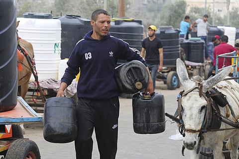 Palestinians arrive to collect drinking water during the ongoing Israeli bombardment of the Gaza Strip in Rafah on Saturday. (Photo | AP)