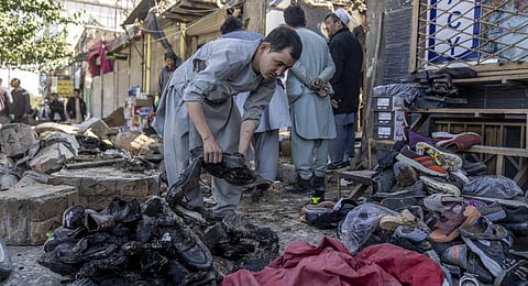 An Afghan man removes the burnt shoes in the site of an explosion in a sports club, in the west of Kabul, Afghanistan. (Photo | AP)