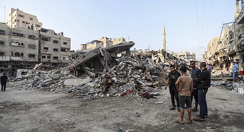 Palestinians inspect the damage of destroyed buildings caused by the ongoing Israeli airstrikes on Gaza City. (Photo | AP)