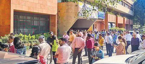 Employees come out of their offices and wait outside after back-to-back tremors were felt due to an earthquake, in New Delhi on Tuesday afternoon | PTI