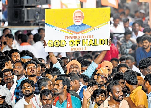 A supporter holds up a poster hailing the National Turmeric Board announcement during the Induru Praja Garjana in Nizamabad on Tuesday | Vinay Madapu