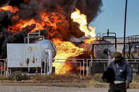 A man walks close to a fire raging at the Zarba oil facility in al-Qahtaniyah in northeastern Syria close to the Turkish border on October 5, 2023. (Photo | AFP)