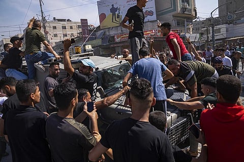 Palestinians gather around an Israeli army vehicle that Palestinian militants drove from Israel into Gaza. (Photo | AP)