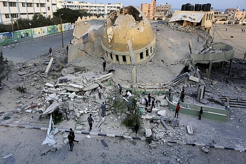 People stand outside a mosque destroyed in an Israeli air strike in Khan Younis, Gaza Strip, Sunday, Oct.8, 2023. (Photo | AP)