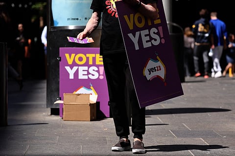A ‘YES23’ campaign volunteer hands out pamphlets as he carries a promotional referendum poster in central Sydney on October 9, 2023. (Photo | AFP)