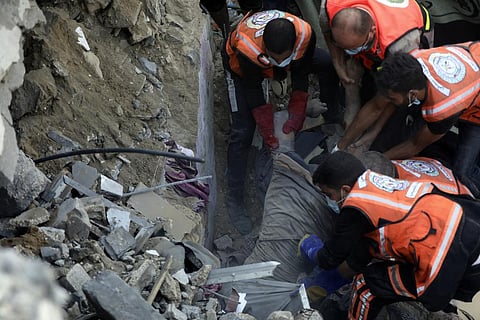 Palestinian rescuers pull a dead body from under the rubble of buildings that were destroyed by Israeli airstrikes in Jabaliya refugee camp. (Photo | AP)