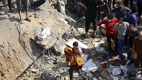 A Palestinian man carries a dead child that was found under the rubble of a destroyed building, following Israeli airstrikes in Jabaliya refugee camp, northern Gaza Strip. 
