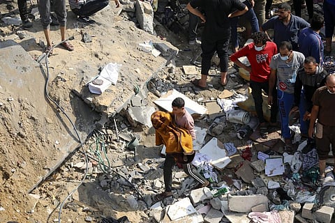 A Palestinian man carries a dead child that was found under the rubble of a destroyed building, following Israeli airstrikes in Jabaliya refugee camp, northern Gaza Strip. (Photo | AP)
