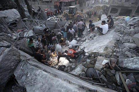 Palestinians look for survivors under the rubble of a destroyed building following Israeli airstrikes in Nusseirat refugee camp. (Photo | AP)