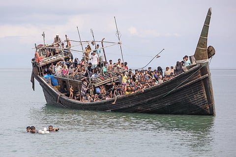 Three newly arrived Rohingya refugees try to swim to the beach as they are stranded on a boat after the nearby community gave them water and food but did not allow them to land. (Photo | AFP)