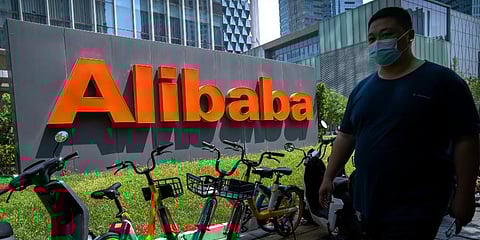 A man wearing a face mask walks past the offices of Chinese e-commerce firm Alibaba in Beijing. (Photo | AP)