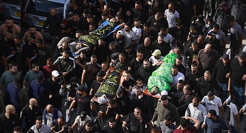 Mourners carry bodies wrapped with the flags of Palestinian militant groups Hamas after they were killed during an overnight Israeli raid in Jenin refugee camp | AFP
