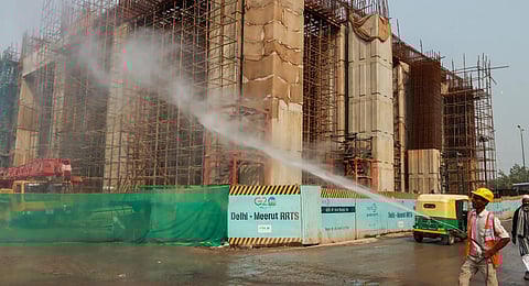 A worker sprays water to curb air pollution at an under-construction building, at Sarai Kale Khan area in New Delhi. (Photo | PTI)