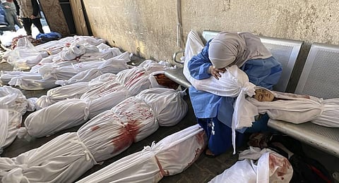 A Palestinian woman reacts over the body of a child as she sits by bodies of Palestinians killed by Israeli airstrikes on Jabaliya refugee camp. (Photo | AP)