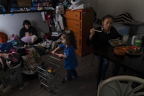Deneffy Sánchez, left, looks at his smartphone on a bunk bed he shares with his mother Lilian Lopez, right, and sister, Jennifer,  in a shared studio apartment in LA, Sept 9, 2023. (Photo | AP)