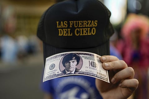 A supporter of Javier Milei holds a reproduction of a hundred-dollar bill featuring the candidate's face outside his campaign headquarters in Buenos Aires, Nov. 19, 2023. (Photo | AP)