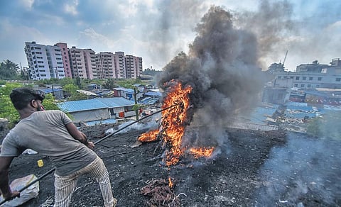 A man burns plastic wires to extract copper near Mali Sahi in Bhubaneswar. (Photo | DEBADATTA MALLICK, EPS)