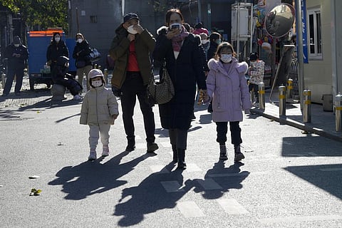 Residents wearing masks pass by a children's hospital in Beijing, Friday, Nov. 24, 2023. (Photo | AP)