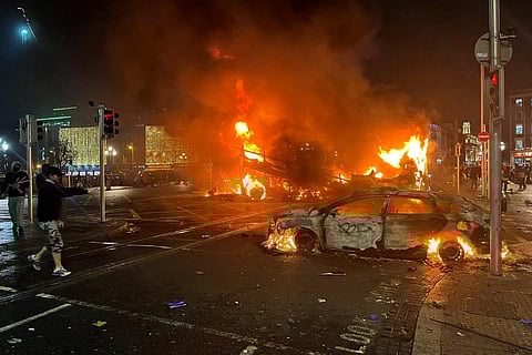 Flames rise from the car and a bus, set alight at the junction of Bachelors Walk and the O'Connell Bridge, in Dublin on November 23, 2023. (Photo | AFP)