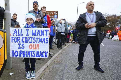 A child holds a placard reading 'All I want for Christmas is our ten points back' prior to the start of the EPL soccer match between Everton and Manchester United on Nov. 26, 2023. (Photo | AP)