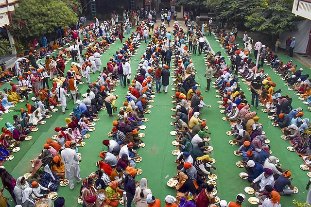 People eat 'prasad' during a langar on Guru Nanak Jayanti, in Varanasi. (Photo | PTI)