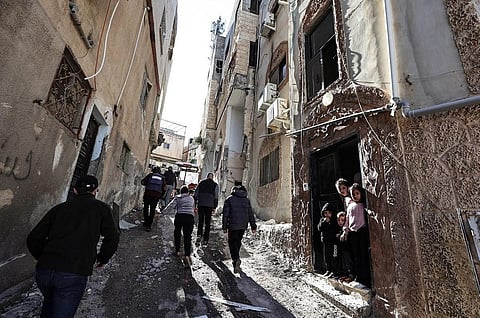 People walk along a damaged street following an Israeli raid in the occupied West Bank city of Jenin on November 29, 2023. (Photo | AFP)