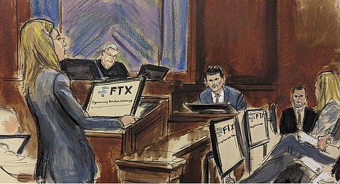 In is courtroom sketch, Sam Bankman-Fried, far left, stands as the jury foreperson, standing far right, reads the verdict with Judge Lewis Kaplan presiding on the bench in Manhattan federal court. (Ph