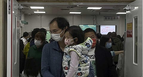 A man carriers a child walk out from a crowded holding room of a children's hospital in Beijing on Oct. 30, 2023.  (AP)
