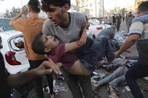An injured Palestinian boy is carried from the ground following an Israeli airstrike outside the entrance of the al-Shifa hospital in Gaza City, Nov 3, 2023. (Photo | AP)