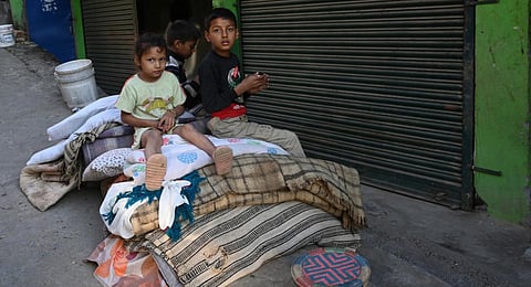 Children sit with their family belongings outside their home in Jajarkot district. (Photo | AFP)