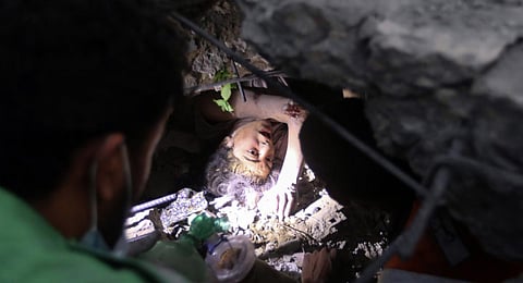 Palestinians try to rescue a girl stuck under the rubble of a destroyed building following Israeli airstrikes in Nusseirat refugee camp. (Photo | AP)