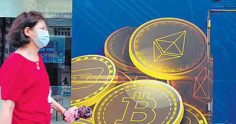 Representational Image: A woman walks past an advertisement for Bitcoin in Hong Kong. (Photo | AP)