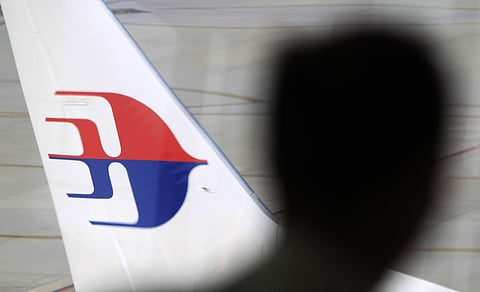 FILE - In this Sunday, March 9, 2014, file photo, a man looks out from a viewing gallery as a Malaysia Airlines aircraft sits on the tarmac at Kuala Lumpur International Airport in Sepang, Malaysia. |