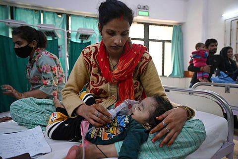 A mother assists her child to breathe with the help of a nebuliser at the emergency ward of the government-run Chacha Nehru Bal Chikitsalaya children hospital in New Delhi. (AFP)