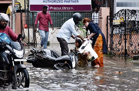 Passersby help a woman who fell onto a waterlogged street after losing control of her two-wheeler in Chennai on Thursday. (Photo | P Ravikumar)