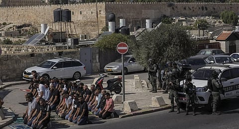 Palestinian worshippers pray outside Jerusalem's Old City while Israeli forces stand guard. (Photo | AP)