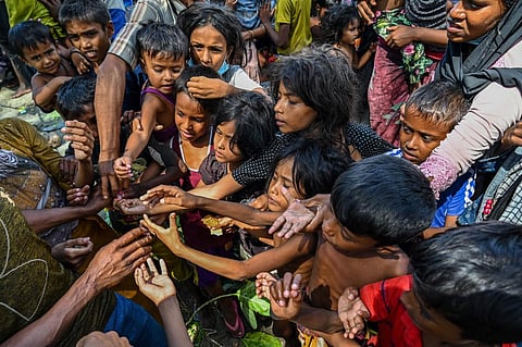 Newly-arrived Rohingya refugees receive food donated by people at a beach in Laweueng, Pidie district in Indonesia's Aceh province on December 10, 2023. (Photo | AFP)
