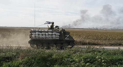 Israeli soldiers patrol as the smoke rises from the Gaza Strip after Israeli strikes on Saturday, Dec. 9, 2023. (AP Photo)