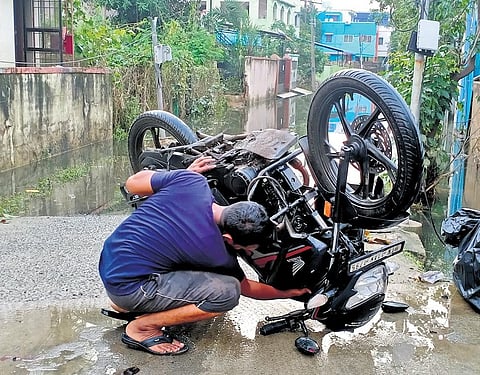 A mechanic trying to repair a two-wheeler which was submerged in water during the recent cyclone in Chennai | P Ravikumar