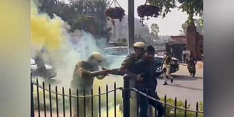 Police personnel detain a man protesting outside the Parliament building carrying a can emitting a yellowish smoke during the Winter session, in New Delhi. (Photo | PTI)