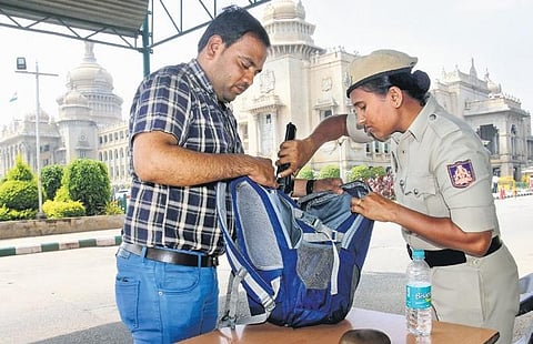 Following the breach in Parliament, a police constable frisks a man and his bag at the entry gate of Vidhana Soudha in Bengaluru on Thursday. (Photo | Vinod Kumar T)