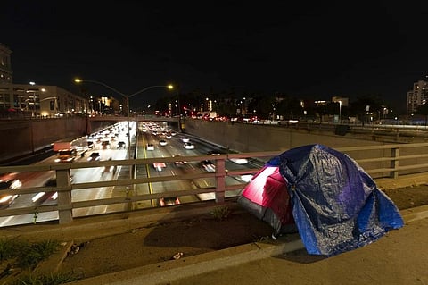 FILE - In this photo illuminated by an off-camera flash, a tarp covers a portion of a homeless person’s tent on a bridge overlooking the 101 Freeway in Los Angeles, Feb. 2, 2023. (Photo | AP)