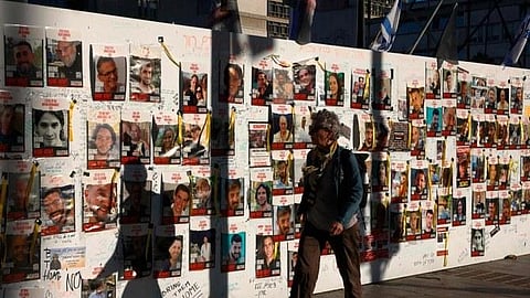 People pass by portraits of Israeli hostages held in Gaza since the October 7 attacks by Palestinian Hamas militants, posted on a wall in Tel Aviv amid the war.